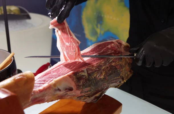 A man slicing a ham from a black Iberian pig