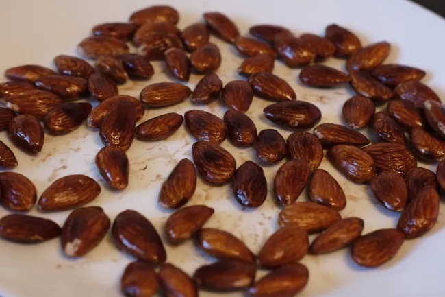 Letting the oil roasted almonds cool down on a plate
